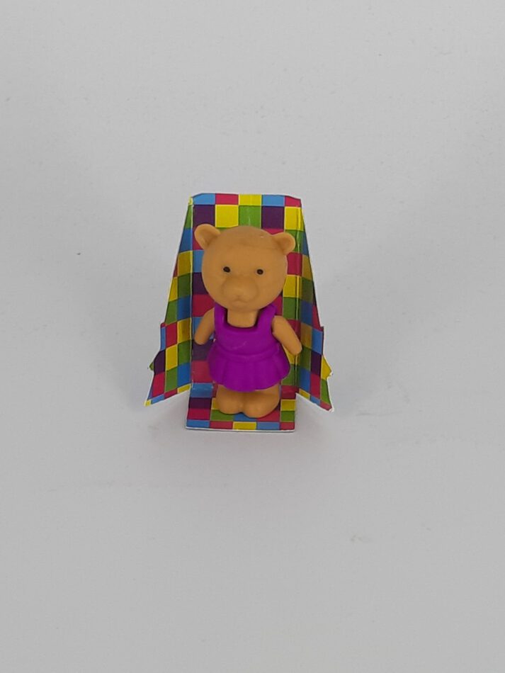 Radiergummi in Form eines kleinen Bärchens mit brombeerfarbener Kleidung; stehend, detailreich modelliert, ca. 5 cm hoch, mit kindgerechtem Design und weicher Oberfläche.
