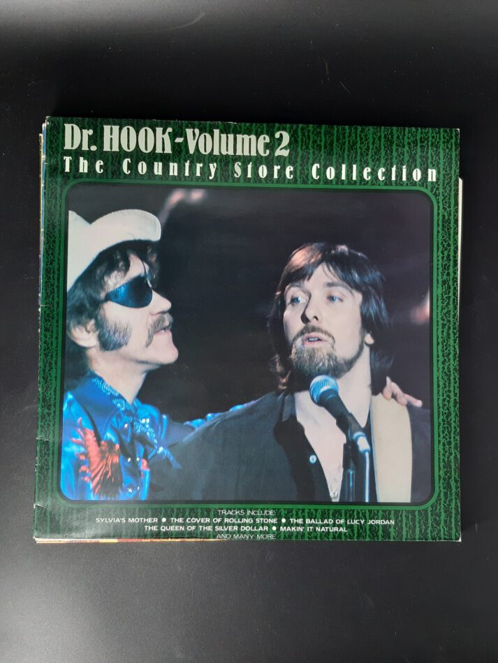 „Schallplatte ‚Dr. Hook – Volume 2‘ in einer gebrauchten LP-Hülle. Das Cover zeigt typisches 80er-Jahre-Design mit Bandfoto oder grafischem Artwork. Enthalten sind bekannte Titel wie ‚Sylvia’s Mother‘, ‚The Cover of Rolling Stone‘, ‚Ballad of Lucy Jordan‘ und weitere Songs aus der Country- und Pop-Rock-Ära. Die Hülle weist altersbedingte Gebrauchsspuren auf, die Vinyl selbst ist geprüft und in gutem Zustand.“