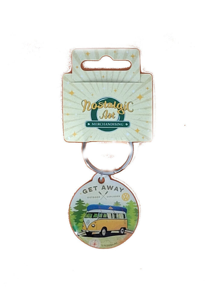 Schlüsselanhänger VW T1 Bulli. Weißes Dach, gelb lackiert und silbernem VW-Logo. Der Anhaenger ist aus Metall und Kunststoff gefertigt und über einen kleinen Ring mit einer Schlüsselkette verbunden. Im Hintergrund Bäume