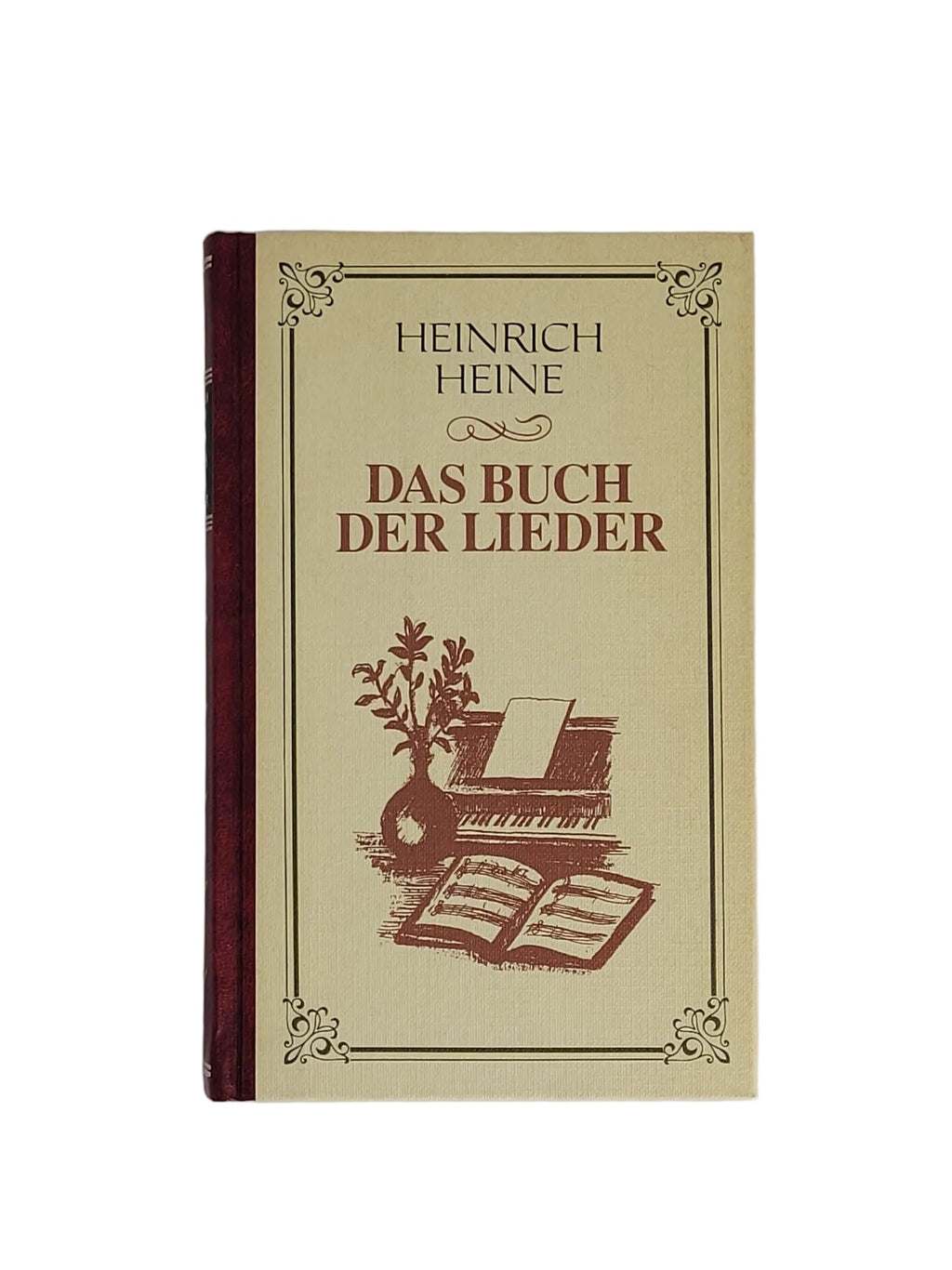 Cremefarbenes Hardcover-Buch "Heinrich Heine - Das Buch der Lieder" aus dem Kaiser Verlag mit weinrotem Rücken und Klavier-Illustration auf weißem Hintergrund.