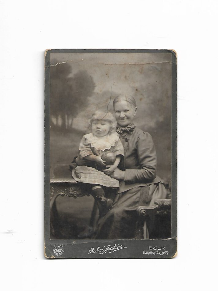 „Historisches Porträtfoto: ältere Frau mit Kind, Photographische Kunstanstalt Robert Spatzier – Eger; ca. 16,5 × 10,5 cm; akzeptabler Zustand; Ecken stark bestoßen.“