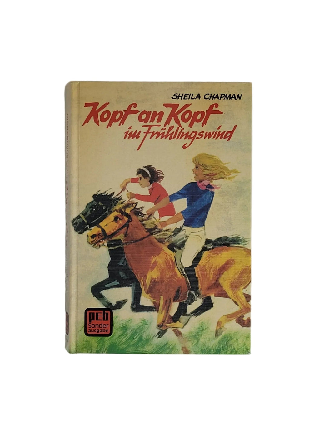Hardcover-Buch "Kopf an Kopf im Frühlingswind" von Sheila Chapman (PEB Sonderausgabe) mit Illustration von zwei galoppierenden Reiterinnen auf Pferden.