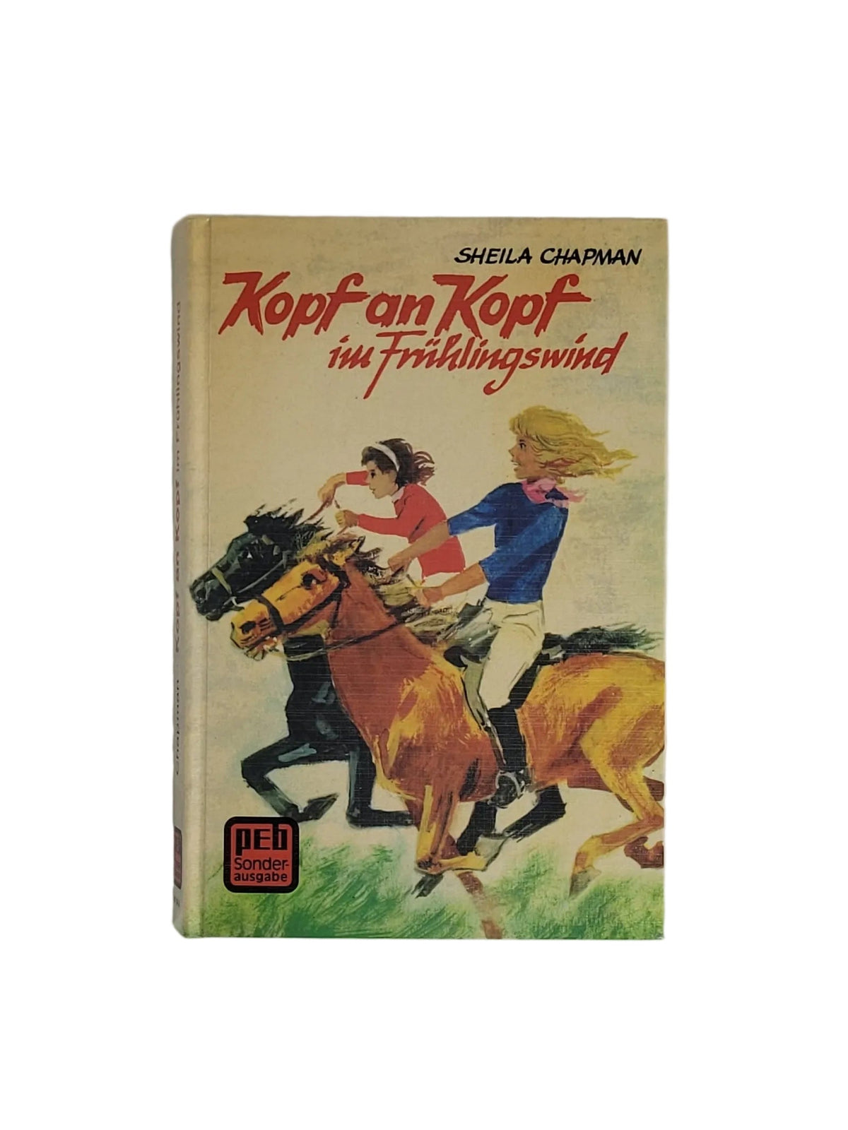 Hardcover-Buch "Kopf an Kopf im Frühlingswind" von Sheila Chapman (PEB Sonderausgabe) mit Illustration von zwei galoppierenden Reiterinnen auf Pferden.