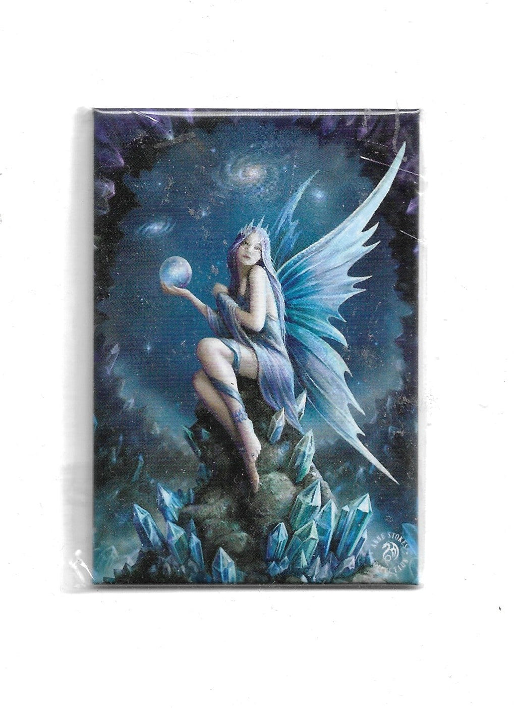 „ Kühlschrankmagnet (8 x 5,5cm) der Anne Stokes Collection. Abgebildet ist eine zarte Eisfee mit transparenten Flügeln, die auf einer blauen Kristallformation sitzt und eine leuchtende Glaskugel in der Hand hält vor einem dunklen Galaxie-Hintergrund.“