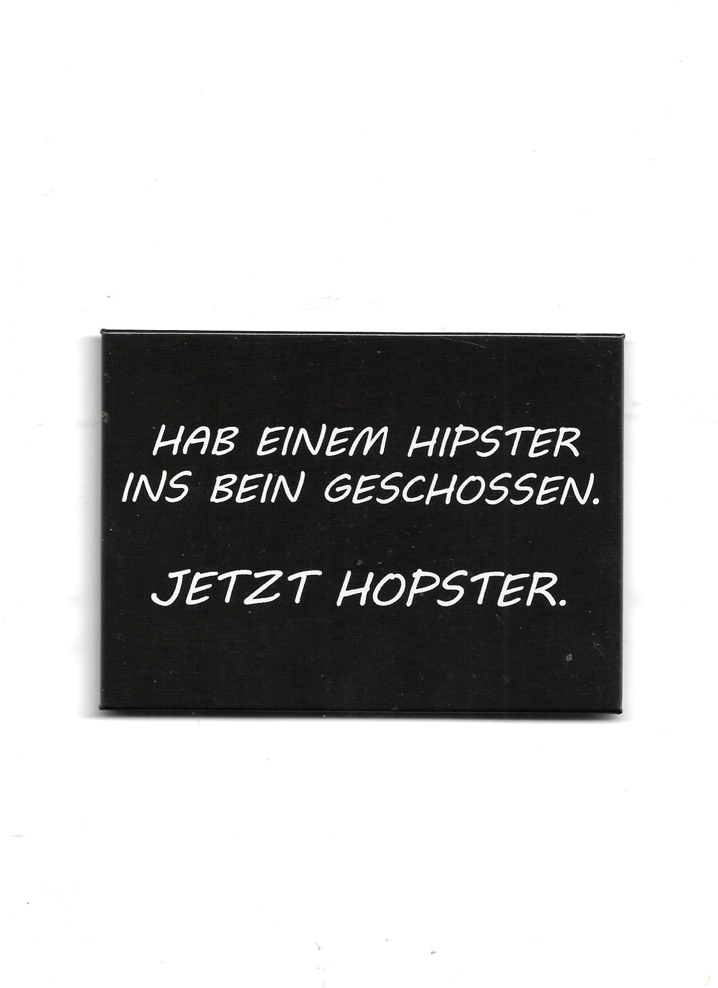 „Rechteckiger Kühlschrankmagnet ‚Hab einem Hipster ins Bein geschossen. Jetzt Hopster‘; farbig bedrucktes, stabiles Blech; vollflächiger Magnet; Format ca. 6,5 × 9 cm; geeignet zum Befestigen mehrerer Notizzettel.“