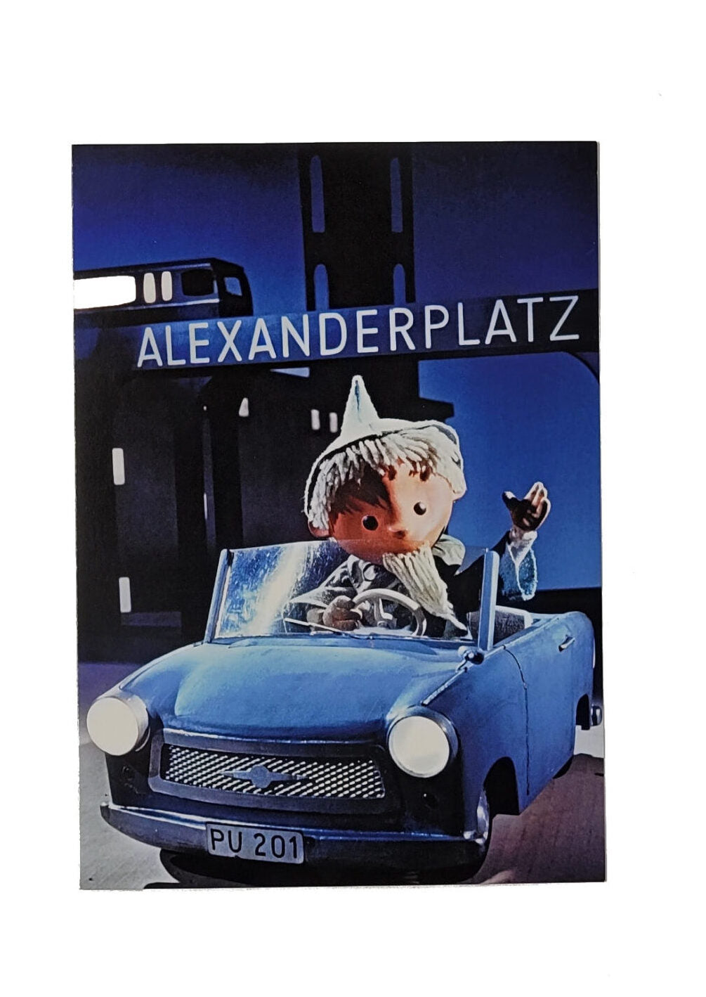 „Postkarte A6 ‚Sandmännchen Berlin Alexanderplatz‘; stabiles Papier, satte Farben, gute Druckqualität, Format 10,5 × 14,8 cm, neu, EAN 4017272024609, Hersteller Anderskartig – Modern Times GmbH.“ 