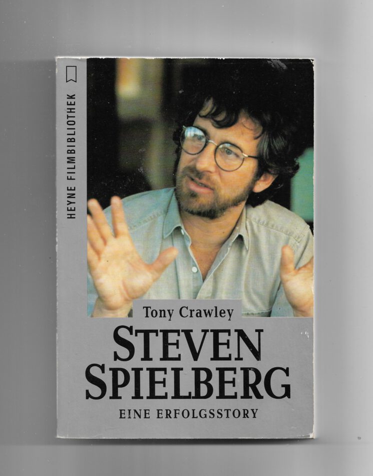 „Cover des Buches Steven Spielberg: Eine Erfolgstory von Tony Crawley, Heyne Filmbibliothek 1993. Zeigt ein Porträt von Spielberg und filmische Motive aus seinen bekanntesten Werken.“
