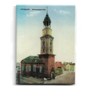 „Magnet mit farbiger Illustration der Hamburger Michaeliskirche. Zeigt barocken Kirchturm mit Kupferdach und Uhr, umgeben von Stadtgebäuden. Text: ‚Hamburg. Michaeliskirche.‘“